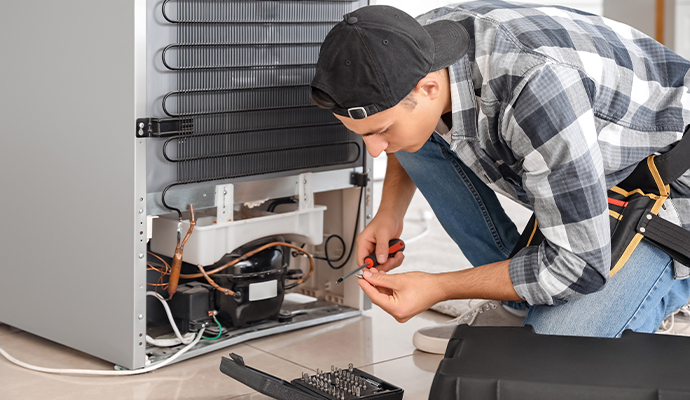 Professional worker repairing refrigerator