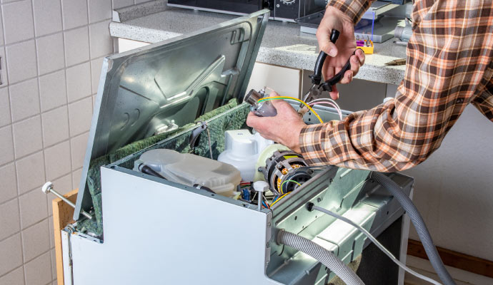 A person repairing a dishwasher with equipment