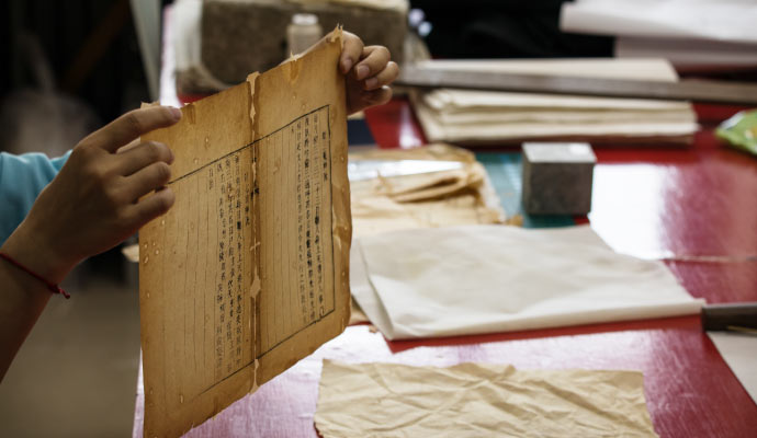 Person carefully holding an damaged document