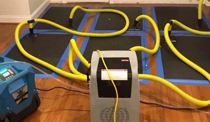 water damage cleanup equipment being used in a room floor