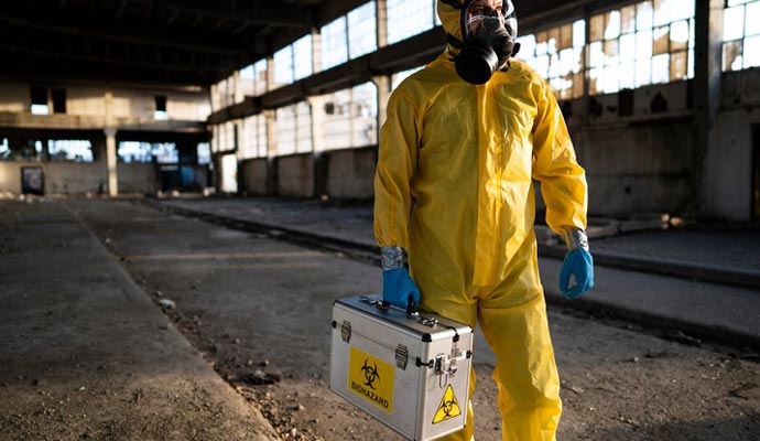 Person in full protective gear with gas mask  to perform biohazard cleanup service