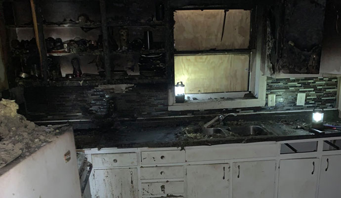 Fire and smoke damaged kitchen interior Kitchen interior showing severe fire and smoke damage on walls and appliances