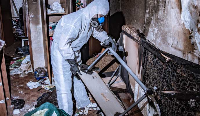 A person is cleaning a fire-damaged room