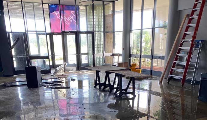 Flooded lobby with scattered debris and cleaning equipment