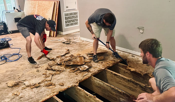 Person removing a damaged wooden floor using equipment